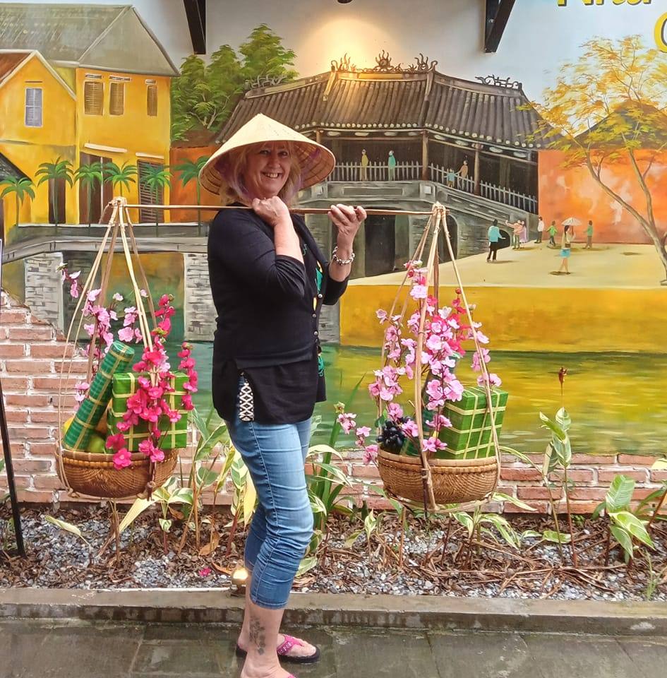 A woman wearing a traditional Vietnamese hat and carrying baskets to sell goods