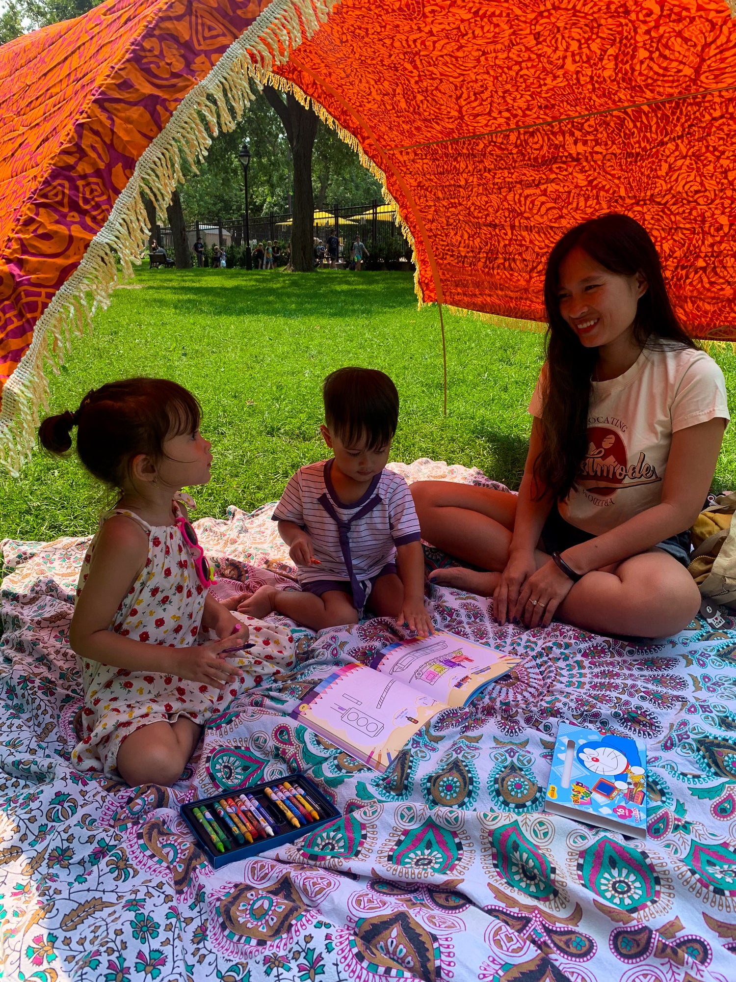 Family sits in the park on their cotton picnic mat by Suniela Beach