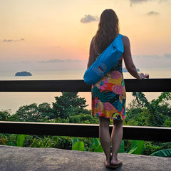 Woman in colourful dress carrying a packed Suniela beach tent while looking out at Thai islands in the sunset_printTurquoiseSuniela